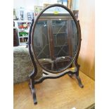 A stained beech oval toilet mirror on scroll feet, 62cm high