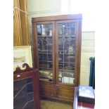 A 1930's oak display cabinet, with two lead glazed doors over two panelled doors on bracket feet,