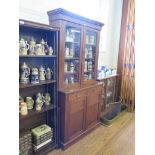 An Edwardian walnut bookcase cabinet, the moulded cornice over a pair of glazed doors, the base with