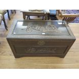 A Chinese camphorwood chest of rectangular form carved with pagodas, figures and boats on stepped