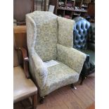 A George II style mahogany and upholstered wing armchair, with deep wings, scroll arms and