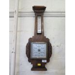 A 1920's oak barometer, of angular form with foliate carving and thermometer, 58cm high