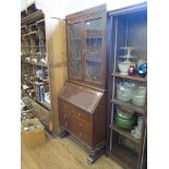 A 1920's oak bureau bookcase, with sunburst lead glazed doors, panelled fall, three long drawers and