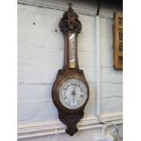 An Edwardian carved oak banjo barometer, the scroll carved frame enclosing a ceramic dial and