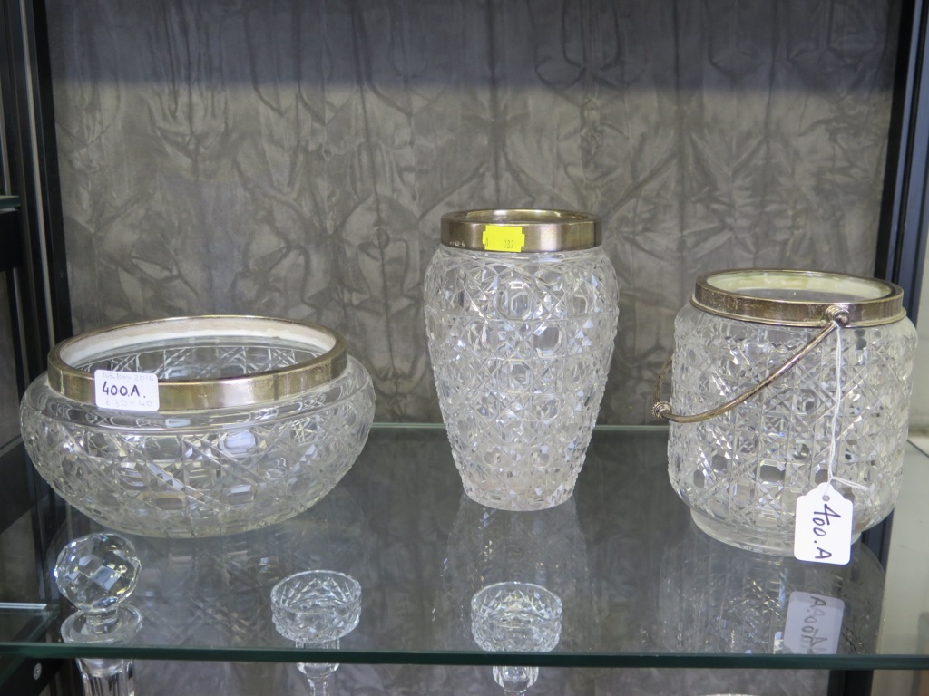 A cut glass biscuit barrel, a cut glass vase with silver rim and a cut glass bowl with a silver rim