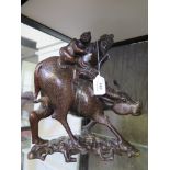 A pair of Japanese hardwood figures, depicting a father and son riding an ox, with inset wire