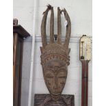 An African softwood carved mask with four feather headdress, 71cm high