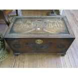 A carved camphorwood chest, the lid depicting figures flanked by boats, on carved paw feet, 101cm