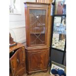 A mahogany veneered corner cabinet with astragal glazed door over a panelled door on bracket feet