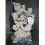 A carved soapstone figure of birds among flowers on a grey marble base, 24cm high