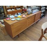 A Danish teak dining room suite by Skovby, the sideboard with five drawers flanked by sliding