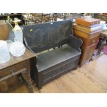 An oak monks bench, the hinged top with lunette carving and cartouche with scrolls to the back