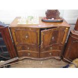 A mahogany serpentine cabinet in the George III style, the twin panelled doors with interior