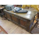 An oak coffer, the double hinged top over a scroll carved frieze and triple panel front, parts