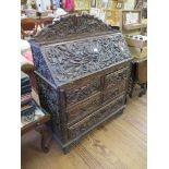 An Anglo-Indian hardwood bureau, profusely and deeply carved with flowers and foliage, the sloping