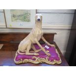 A Large Victorian model of a seated whippet on a purple and gilded scroll base, the underside