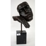 A CONTEMPORARY BRONZE SCULPTURE DEPICTING A FACE RESTING ON A HAND mounted on a marble plinth