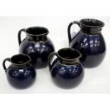 A GRADUATED SET OF THREE 19TH CENTURY POTTERY JUGS, possibly Jackfield, each with deep blue lustrous