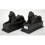 A PAIR OF BLACK PAINTED COMPOSITE BOOK ENDS in the form of recumbent lions, each 23cm wide