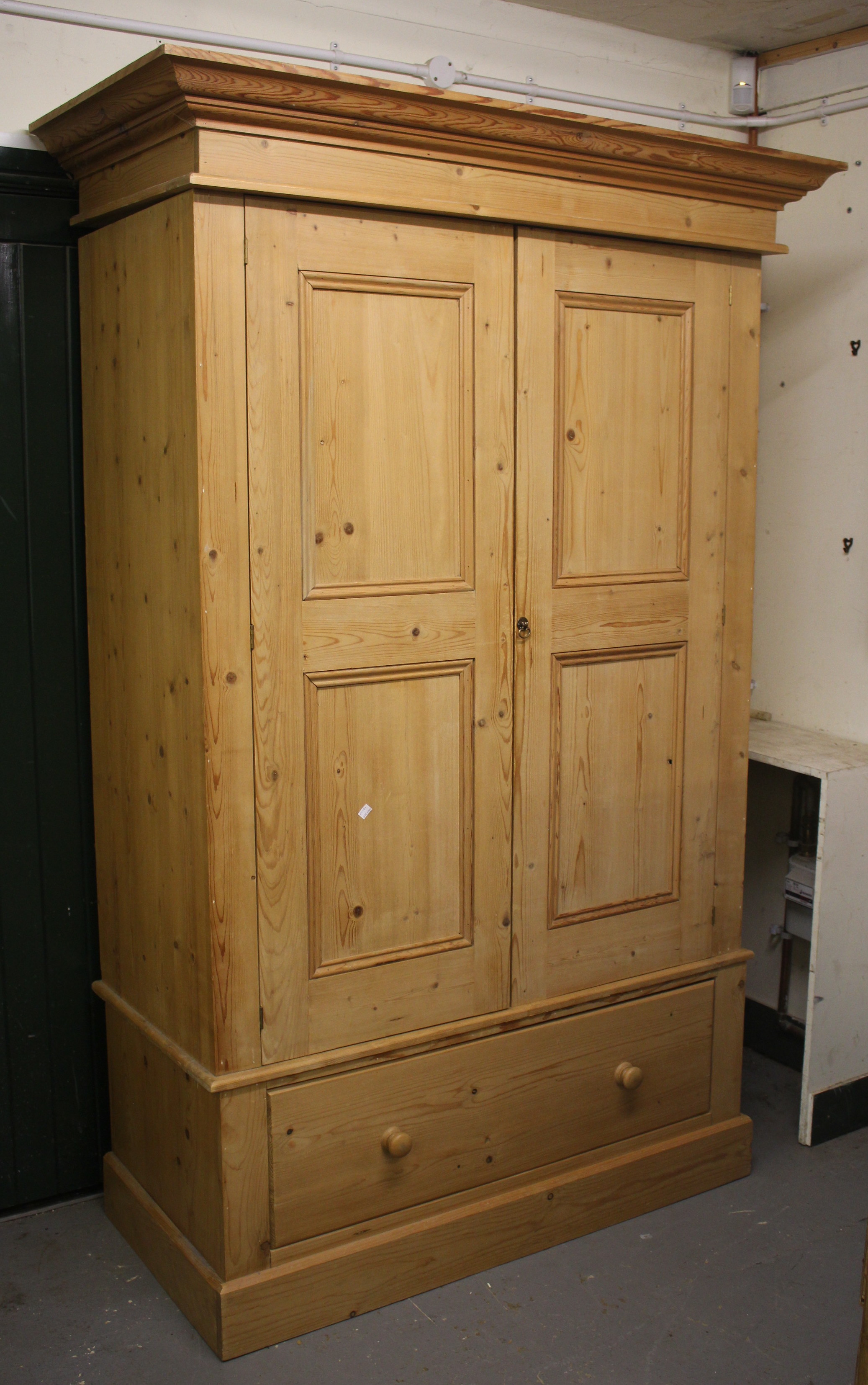 A 20TH CENTURY PINE WARDROBE with two panelled doors above one long drawer with turned knob