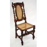 AN ANTIQUE JACOBEAN STYLE WALNUT AND CANED CHAIR with carved scrolling decoration 51cm wide