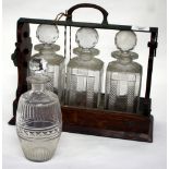 A LATE 19TH / EARLY 20TH CENTURY OAK TANTALUS with three cut glass decanters, 33cm wide and a