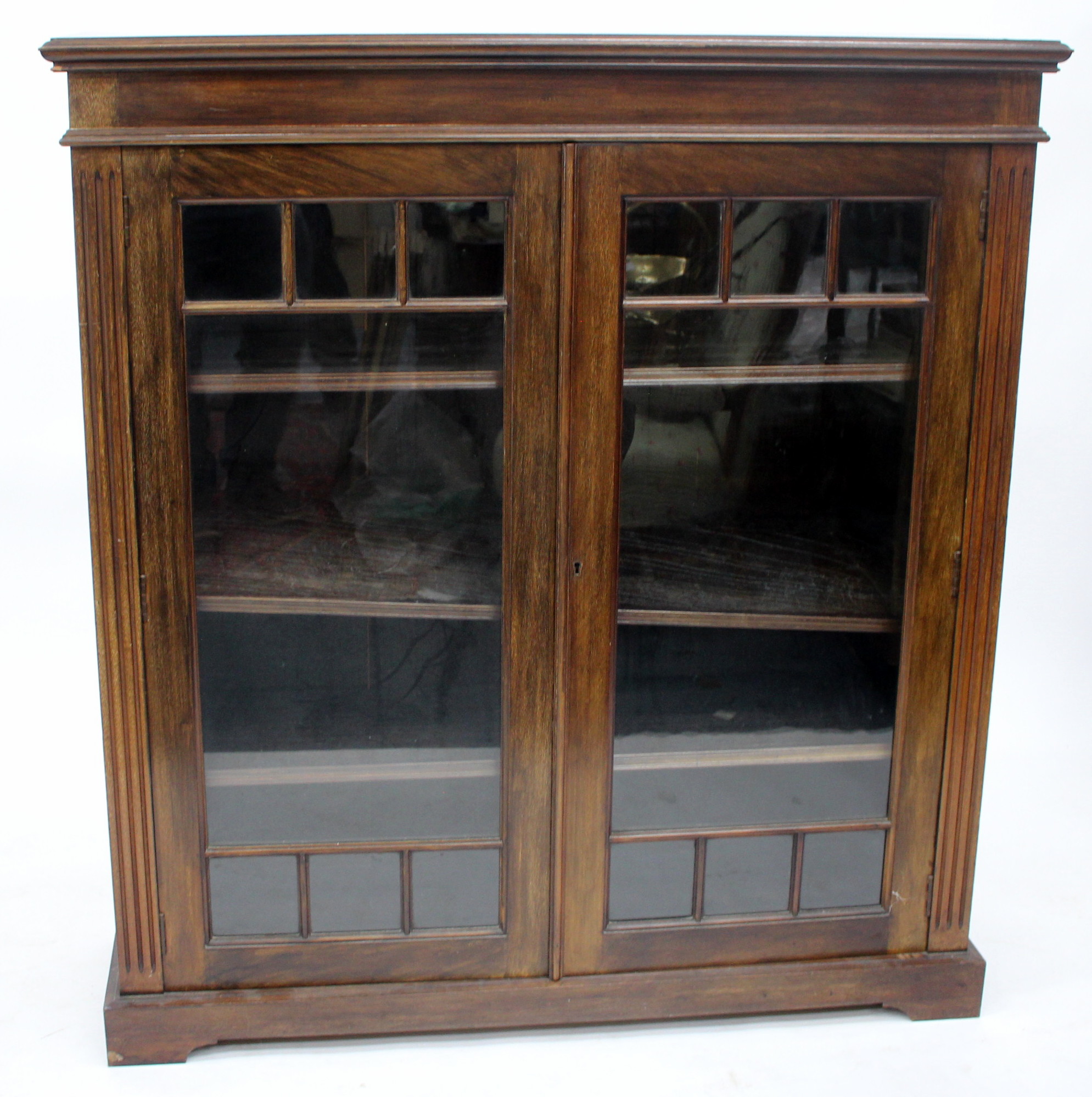 AN EDWARDIAN MAHOGANY GLAZED BOOKCASE with three adjustable shelves and a plinth base 107cm wide