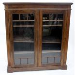 AN EDWARDIAN MAHOGANY GLAZED BOOKCASE with three adjustable shelves and a plinth base 107cm wide
