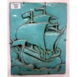 A 20TH CENTURY POTTERY TILE decorated in turquoise glazes and moulded with galleon in the manner