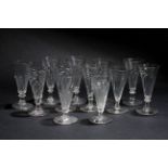 A GROUP OF TWELVE DWARF ALE GLASSES with wrythen decoration to the conical bowls, the largest 13.5cm