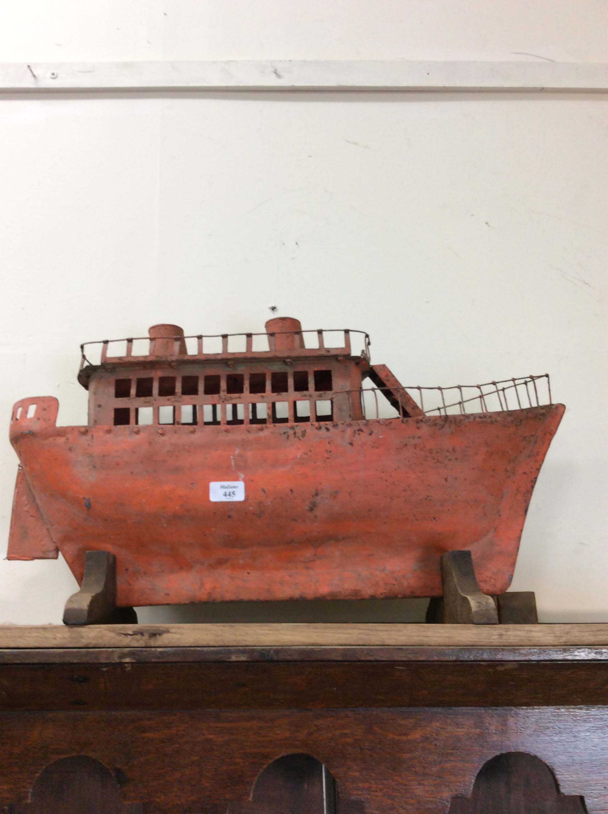 AN EARLY TO MID 20TH CENTURY ORANGE PAINTED TIN PLATE MODEL of a boat 70cm in length, mounted on a