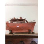 AN EARLY TO MID 20TH CENTURY ORANGE PAINTED TIN PLATE MODEL of a boat 70cm in length, mounted on a