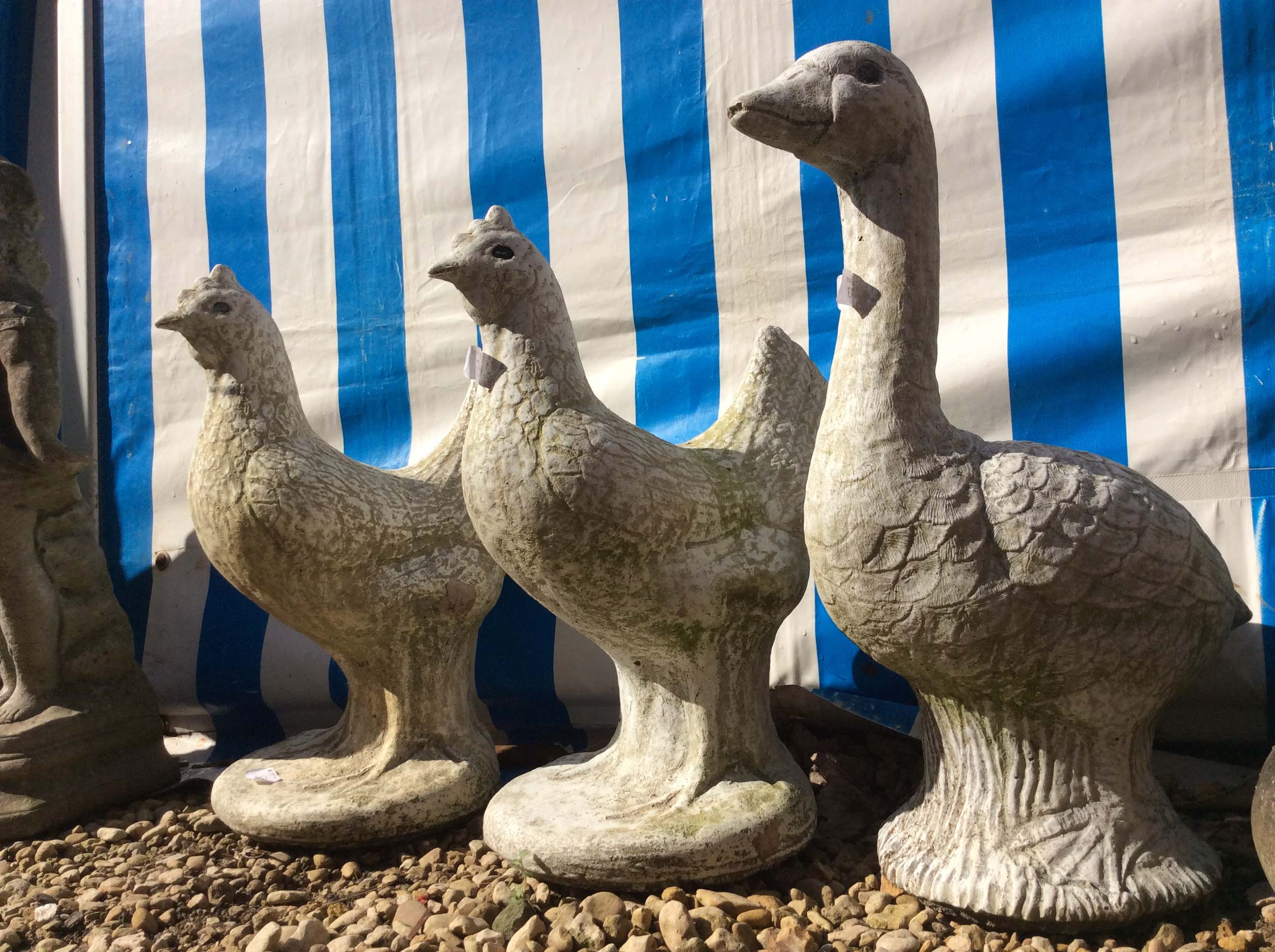 TWO COMPOSITE STONE CHICKENS each 44cm in height, a composite stone goose, two composite stone