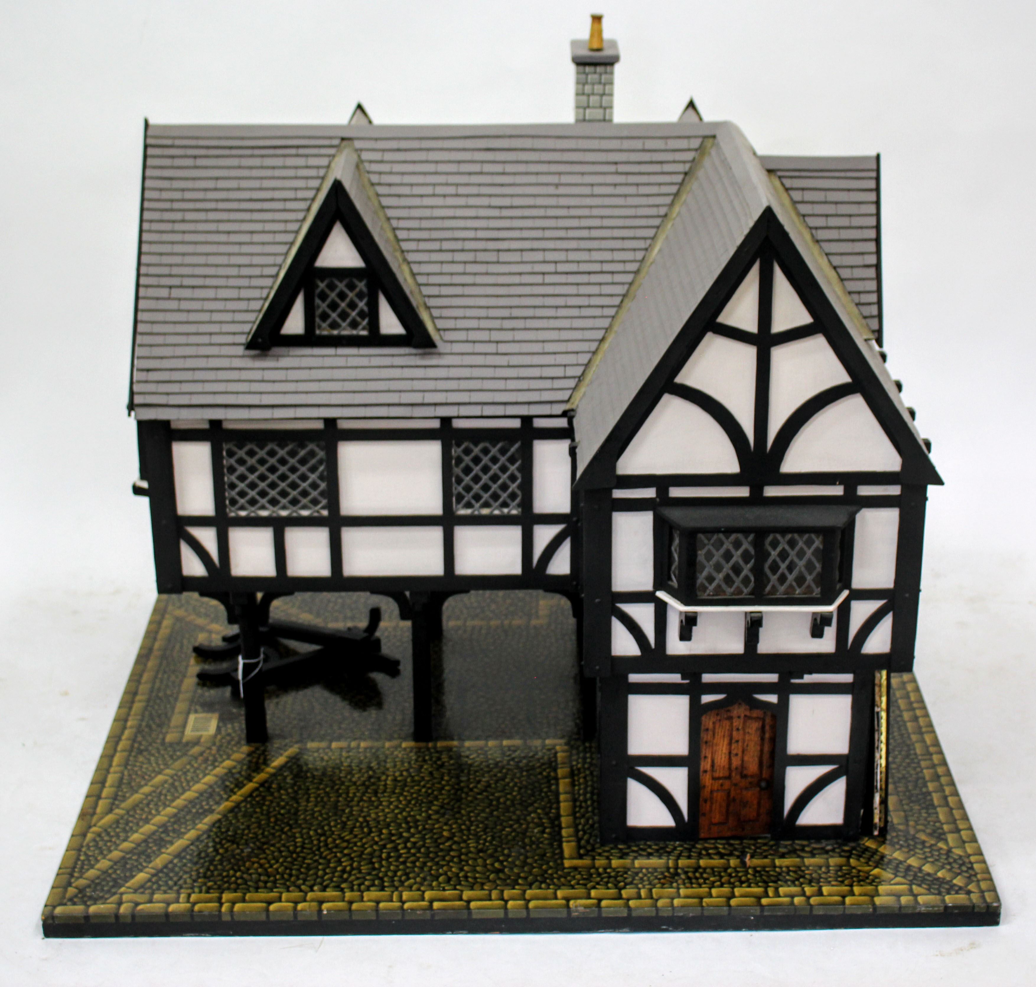 A HANDMADE TUDOR STYLE DOLLS HOUSE painted in black and white, having leaded glass windows and stilt