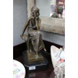 A CONTEMPORARY BRONZE SCULPTURE of a seated girl on a black marble base, 38cm in height