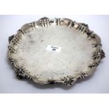 A LATE VICTORIAN SILVER SALVER with a scrolling shaped edge and three feet, made by Thomas