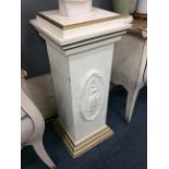 A WHITE PAINTED PLINTH BASE with oval relief decoration of a woman in a dress to the front and on