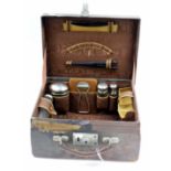 AN ANTIQUE LEATHER SMALL DRESSING CASE with silver plate topped bottles and jars within 33.5cm wide