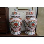 A PAIR OF ORIENTAL BALUSTER VASES AND COVERS decorated in iron red and greens