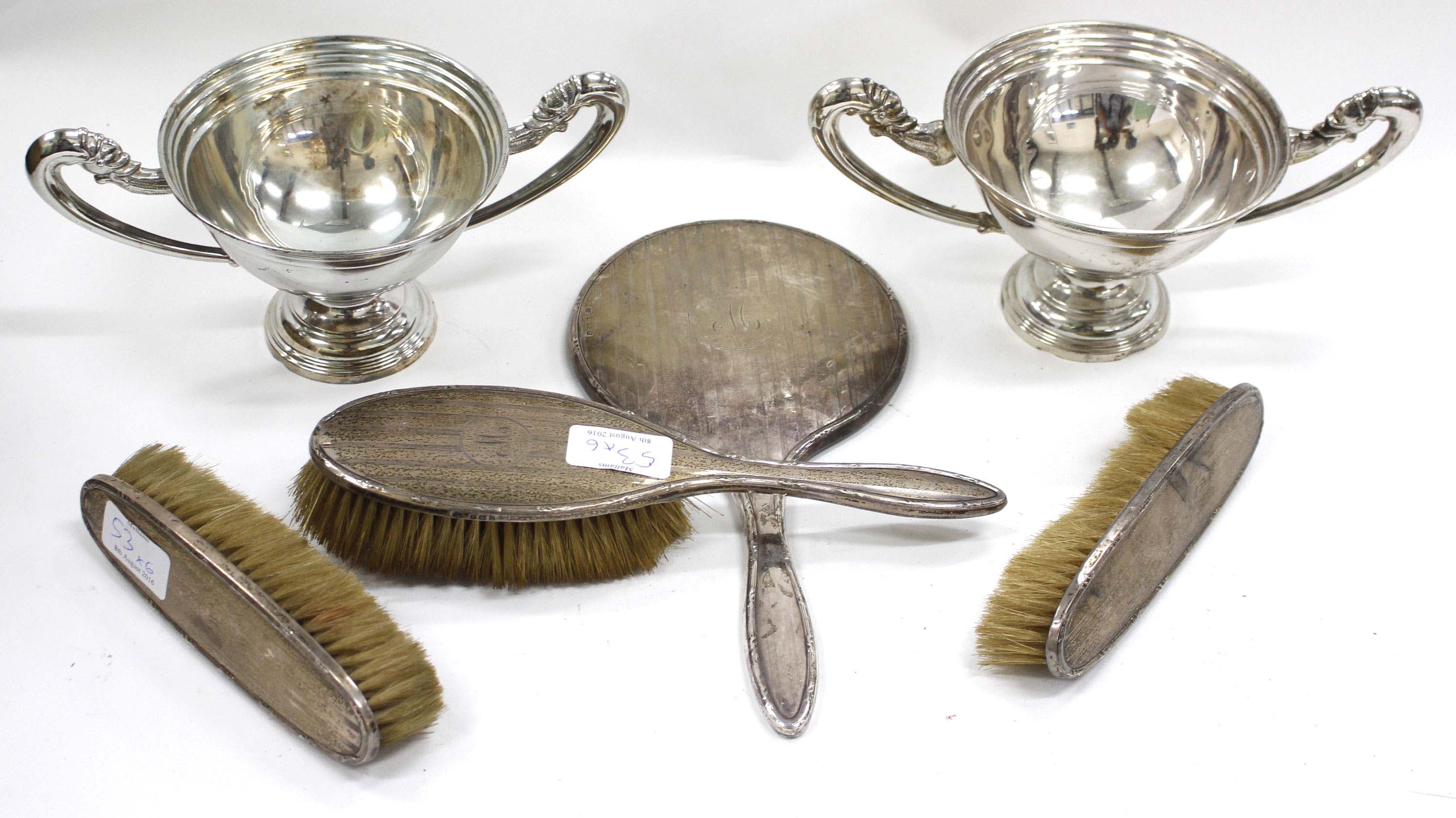 A SILVER BACKED DRESSING TABLE HAND MIRROR together with three matching silver backed brushes and