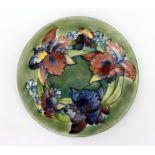 A MID 20TH CENTURY MOORCROFT ORCHID PLATE on green ground with paper label to reverse