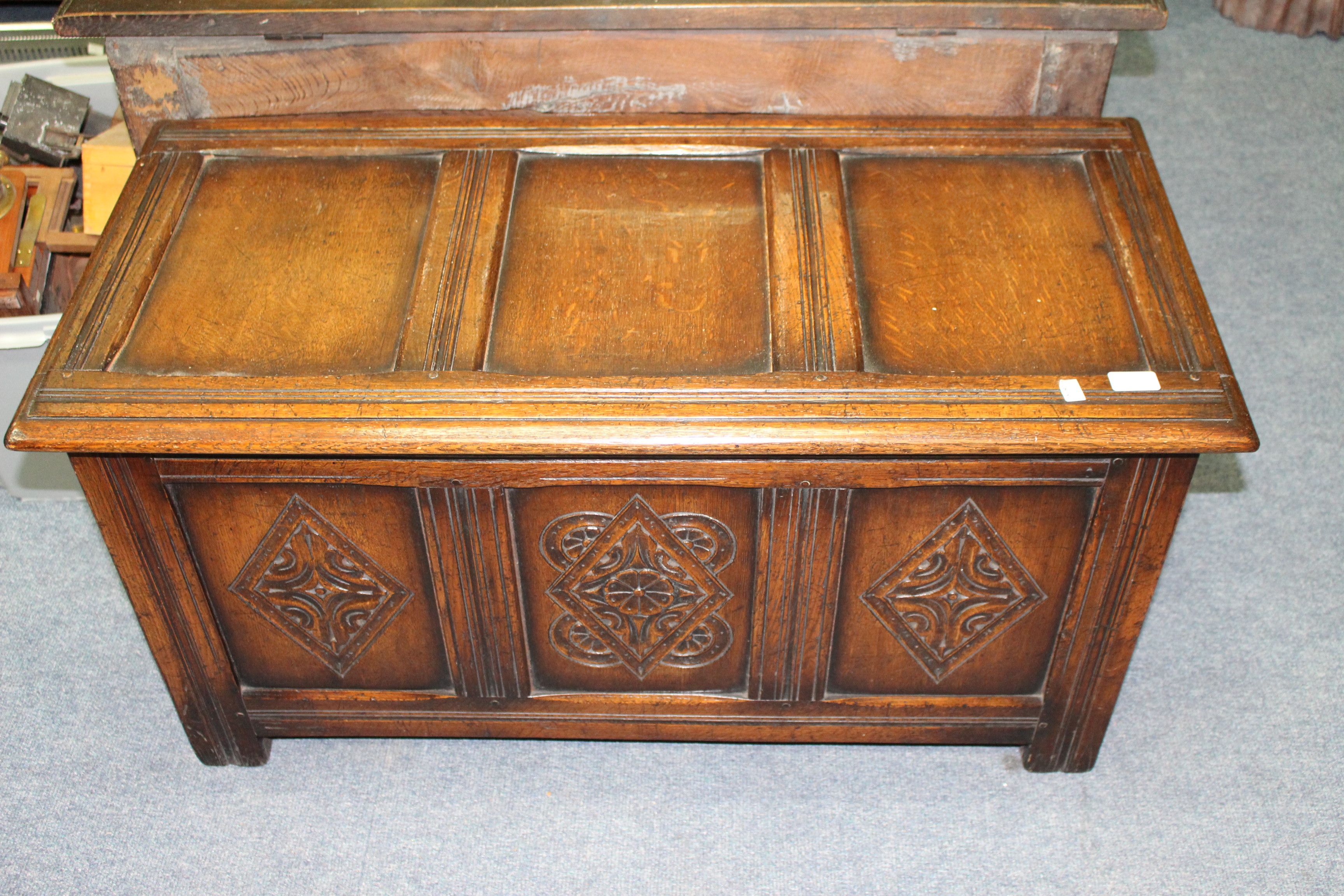 AN OAK COFFER with three panelled top and front and lozenge carved front panels