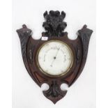 AN EDWARDIAN MAHOGANY ARMORIAL SHIELD BAROMETER with acanthus scroll detail and mask head, 56cm x