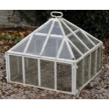 AN OLD WHITE PAINTED CAST IRON CLOCHE with square glazed base surmounted by a pyramidal cover with