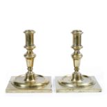 A PAIR OF CAST BRASS CANDLESTICKS with square bases, each 14cm in height