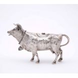 AN ANTIQUE CONTINENTAL WHITE METAL, POSSIBLY SILVER, COW CREAMER with hinged lid and attached cow