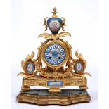 A FRENCH GILT METAL MANTLE CLOCK set with porcelain panels and on a shaped stand 38cm high