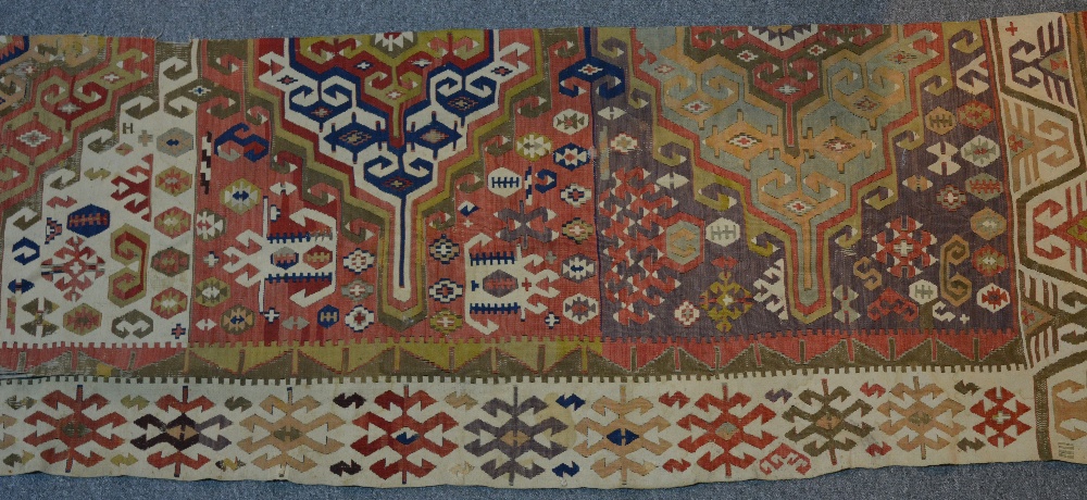 A Kelim half runner with a central panel of purple ground, with a white border including symbols