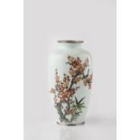 A Japanese cloisonne enamel vase Meiji period with a bird perched amongst blossom, on a white