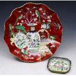 A CHINESE RED GROUND DISH with wavy border decorated vases of flowers with red seal mark, circa